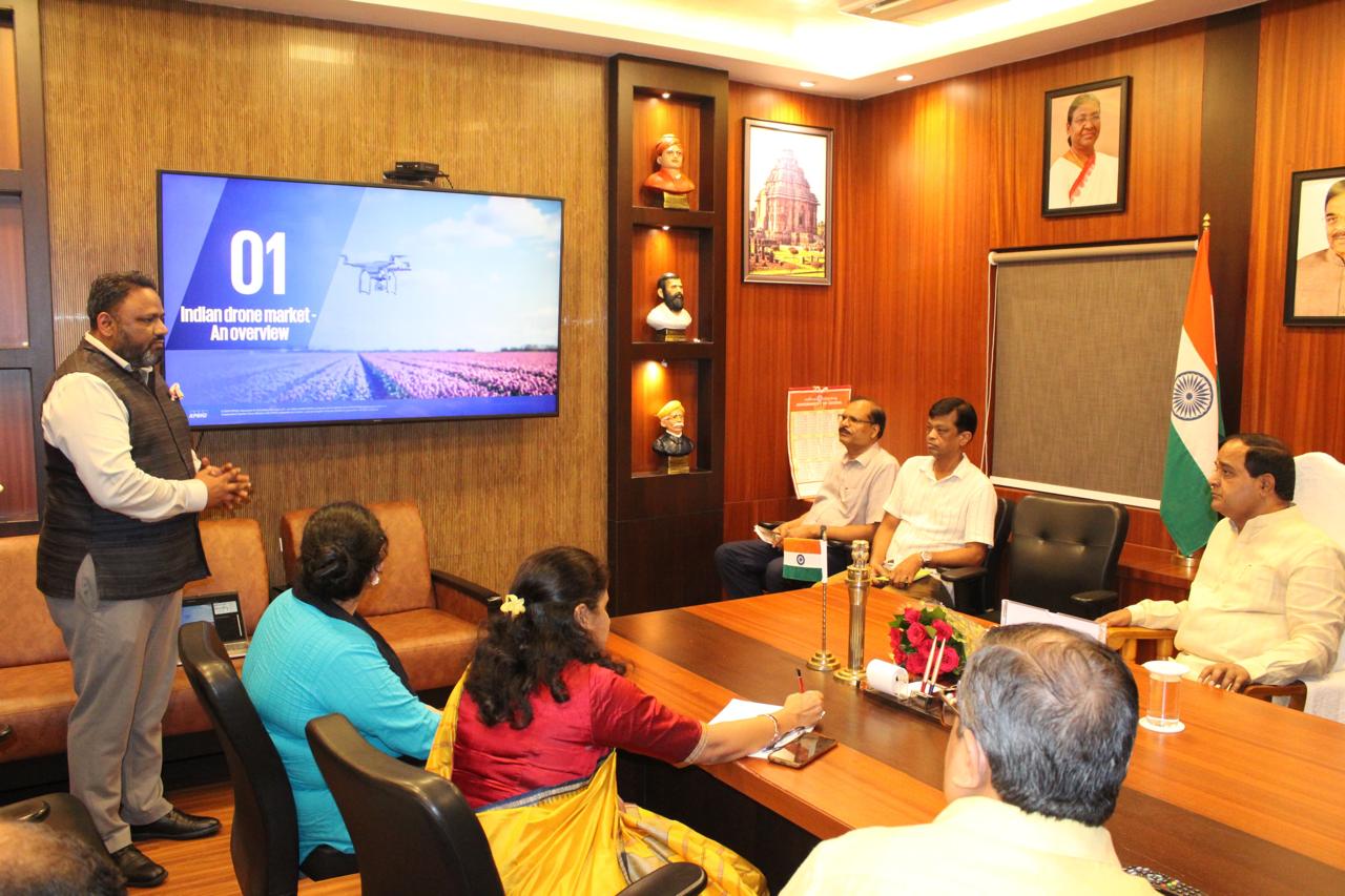 Officials seated in a conference room while a presenter discusses drone mission opportunities on a display screen.
